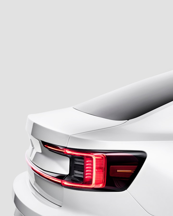 Zoomed in on the red rear lights of a white Polestar 2. Light grey background