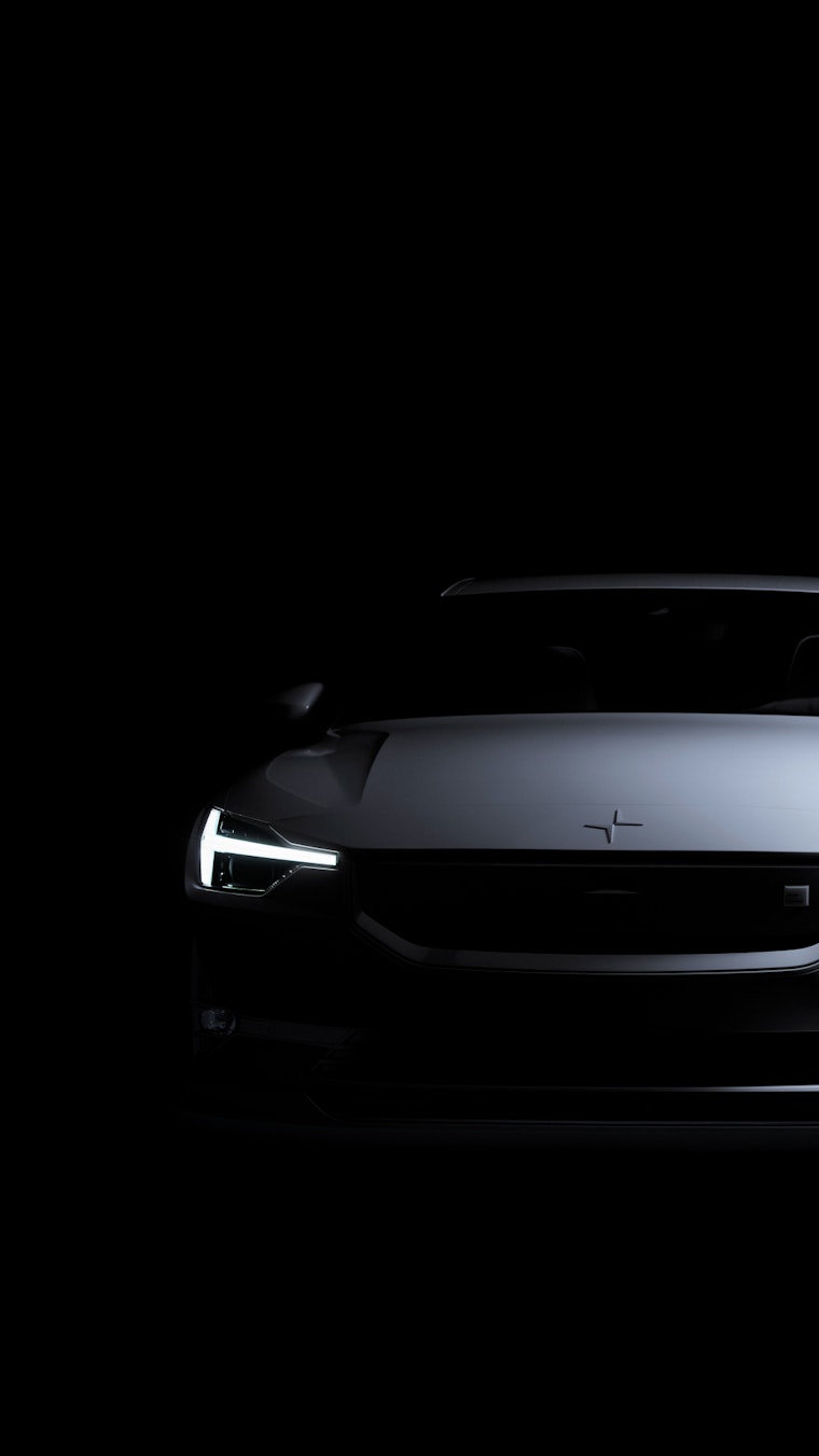Polestar 2 front view in a spotlight, dark space around it