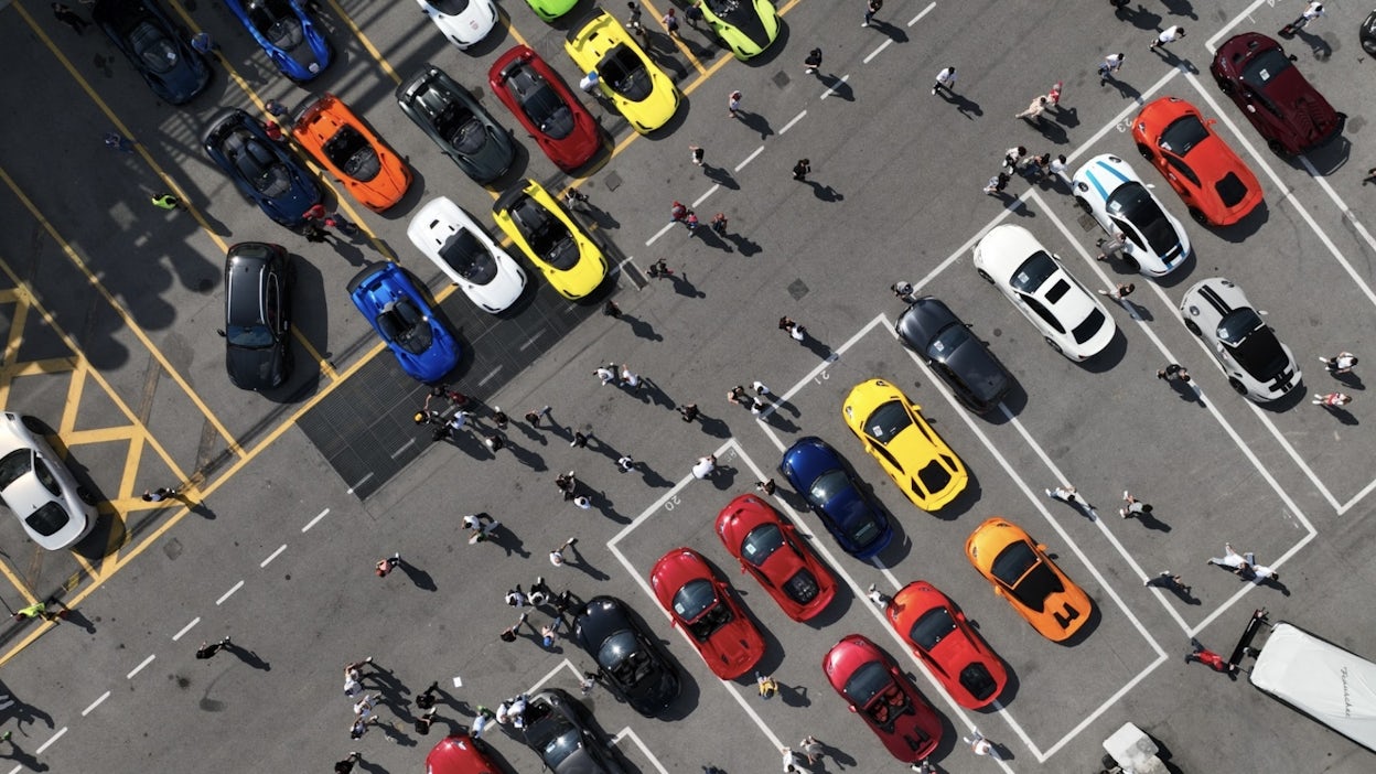 Bird's-eye view of the parking lot at Monza showing colourful cars and people.