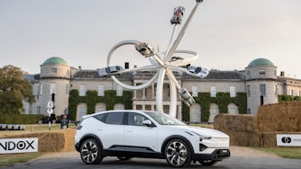 A white Polestar 3 in front of a large building.