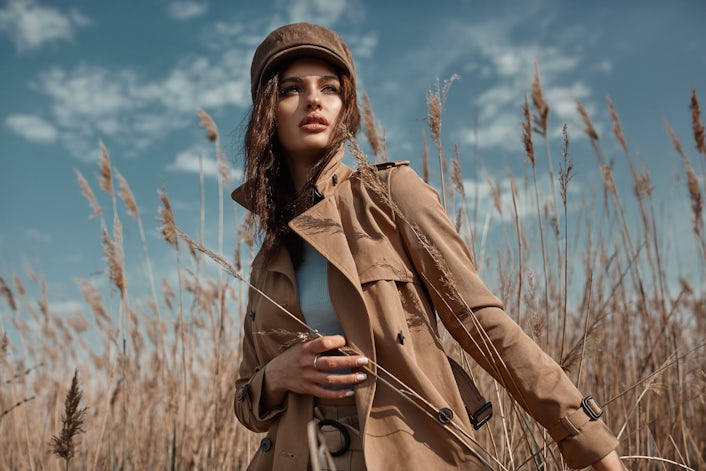 Stylish girl in trench coat in field