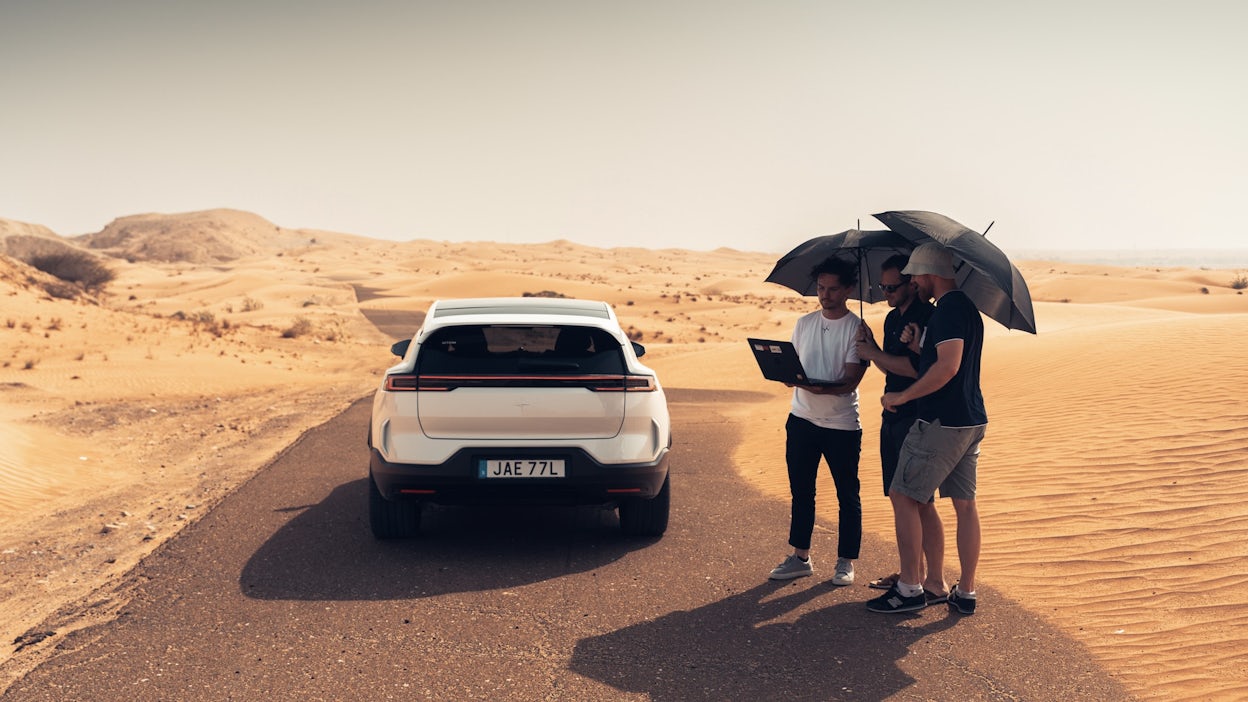 Rear view of Polestar 3 with three people next to it looking at a computer