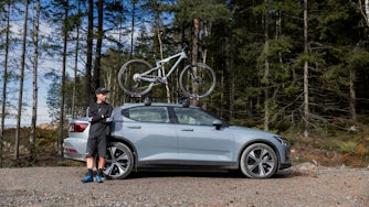 Man leaning on side of Polestar 2 with bike on roof