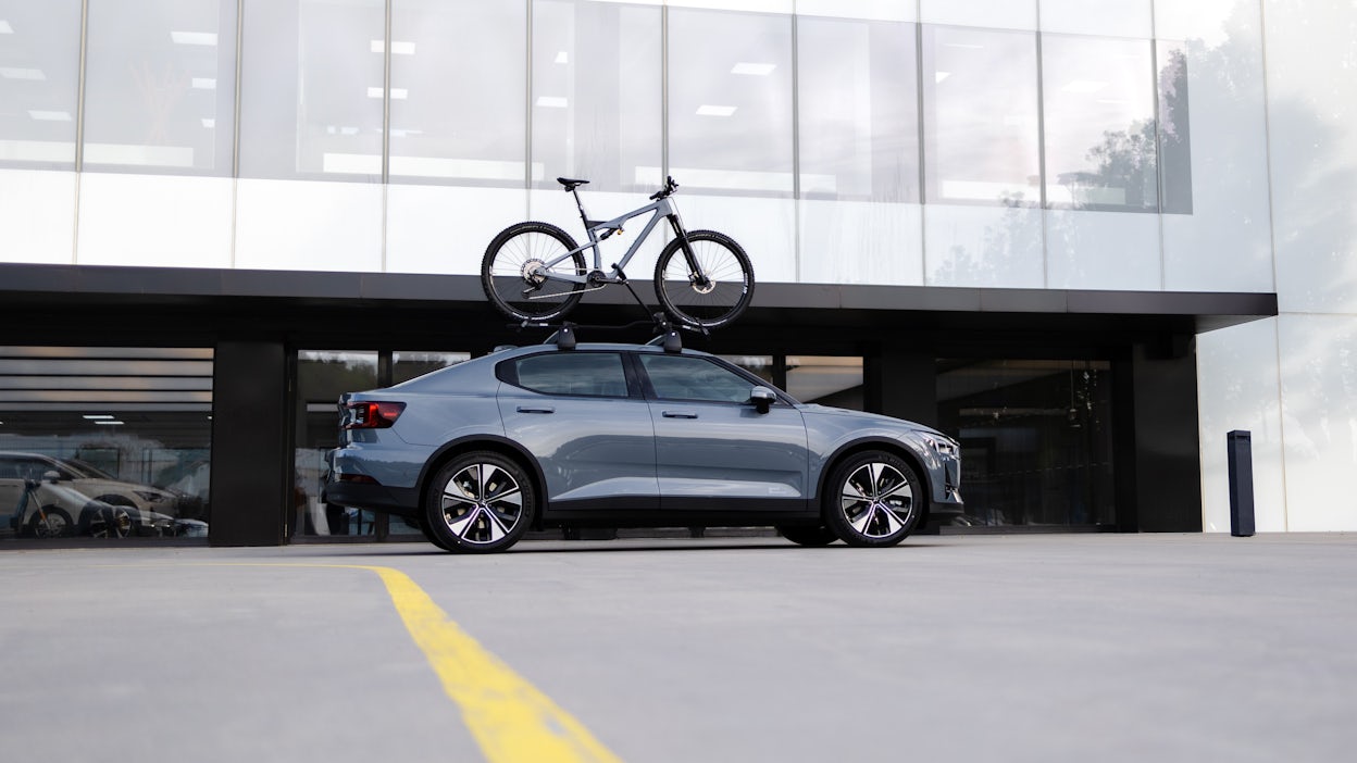 Polestar 2 with Allebike bike on roof in front of white office building