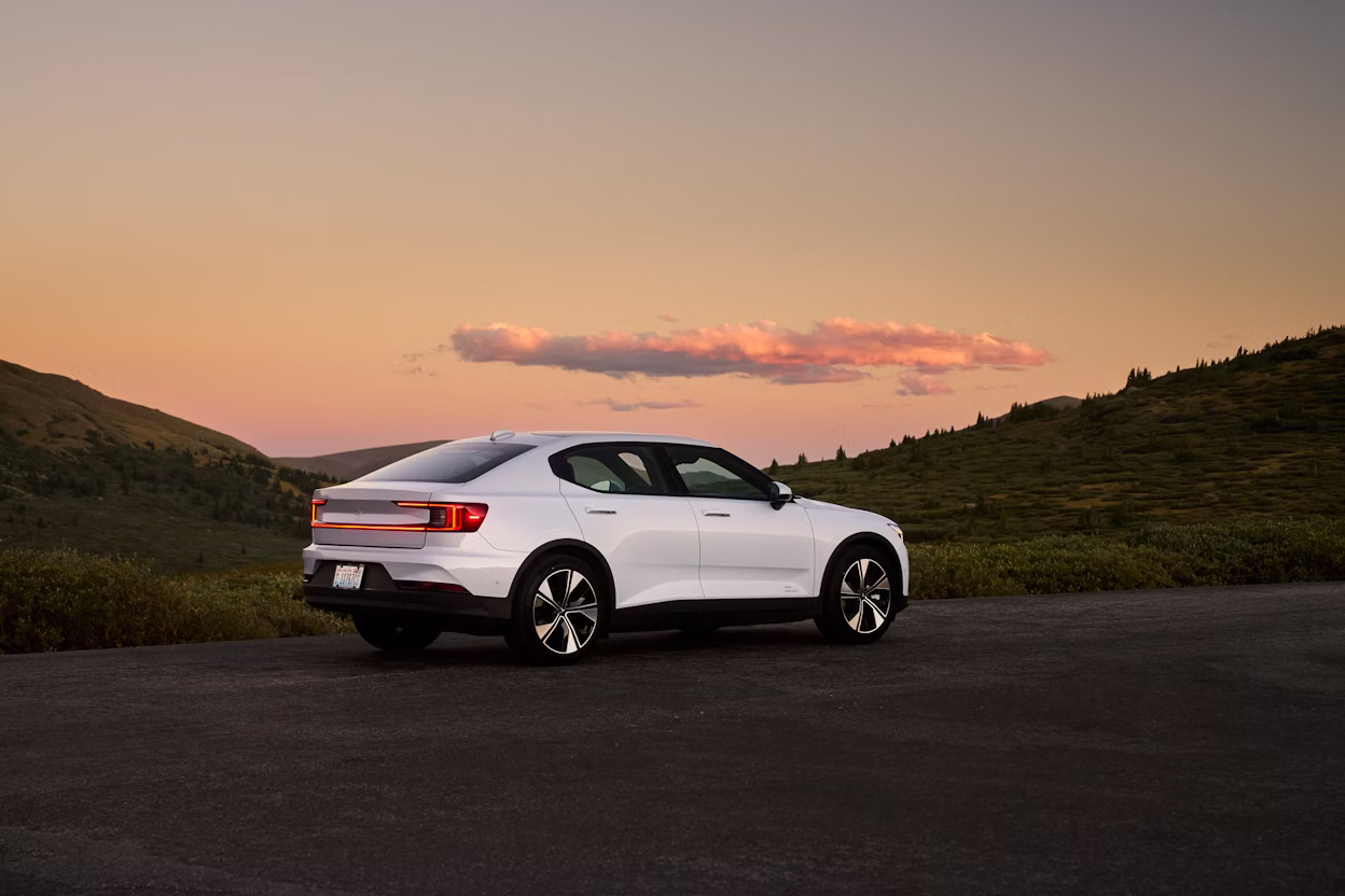 Polestar car parked on road with hills and sunset in background.