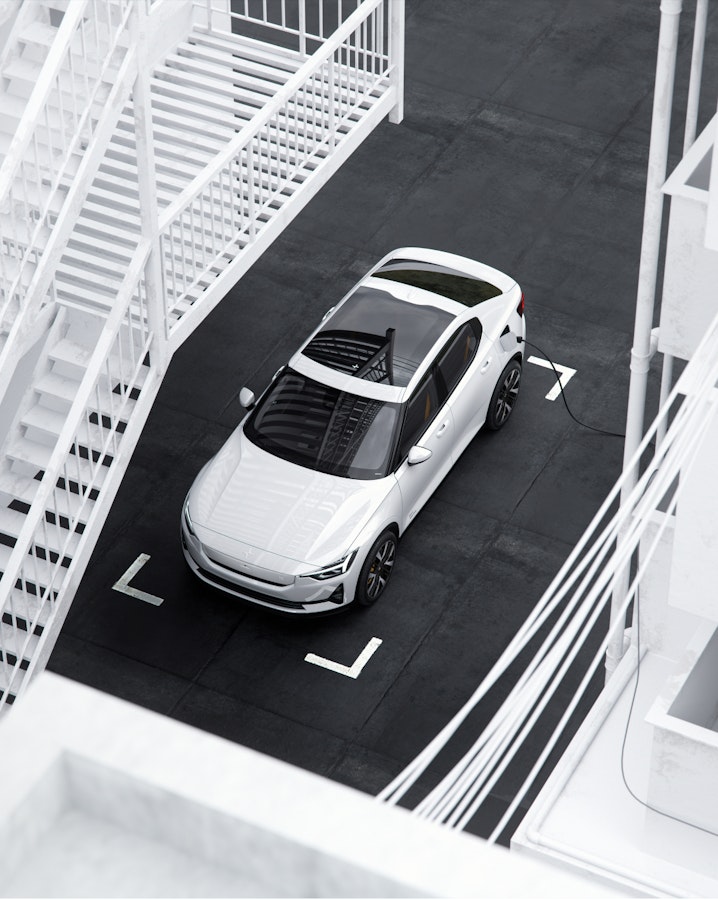 A white Polestar 2 charging in front of Polestar Gothenburg headquarters.