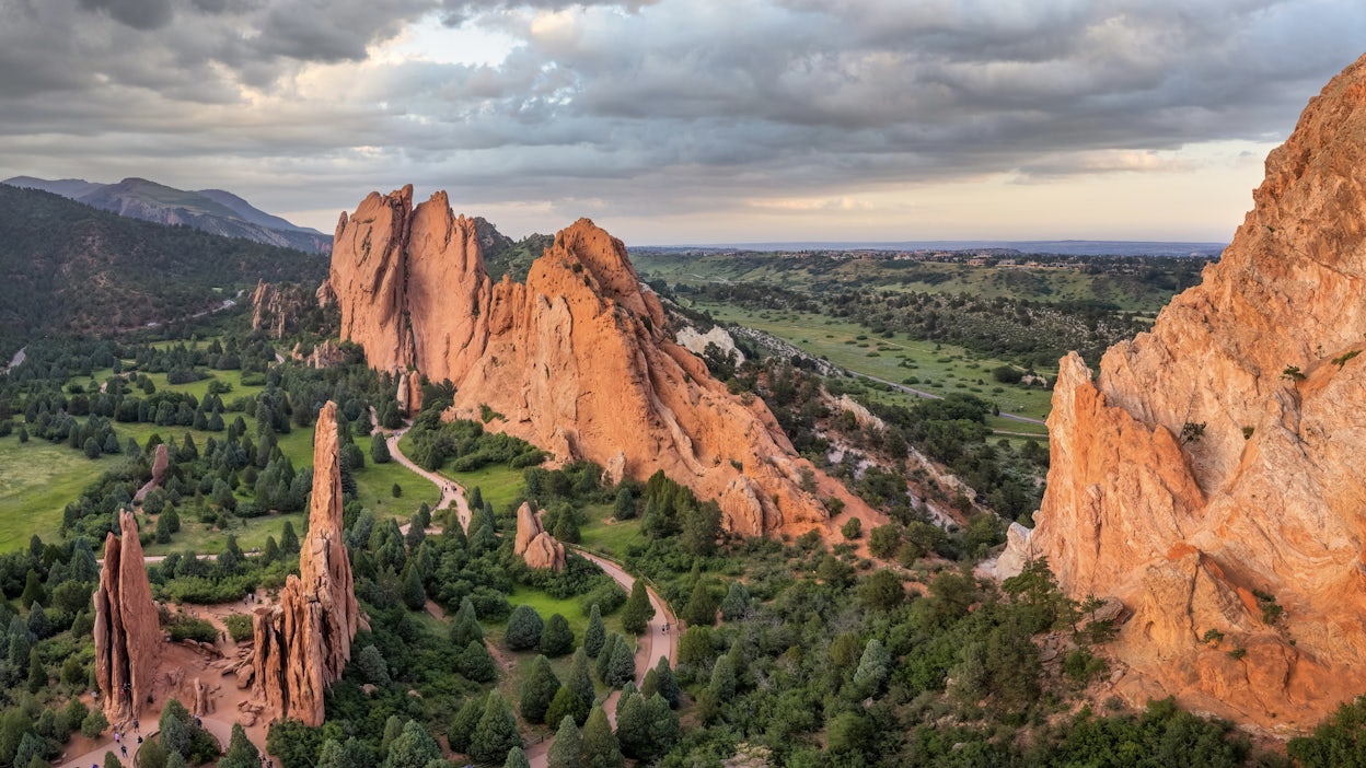 Majestic rock formations against a backdrop of a cloudy sky and lush greenery.