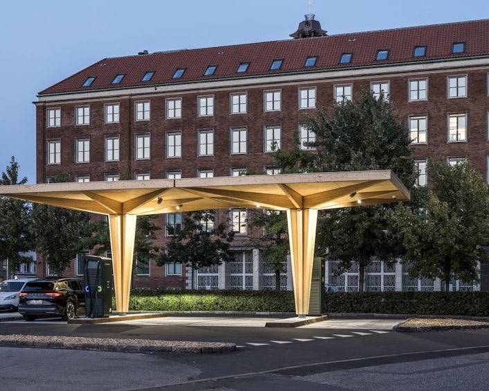 Wooden canopy charging station lit up at night
