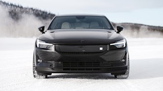 Front view of a pristine black Polestar 2 parked in a snowy landscape.