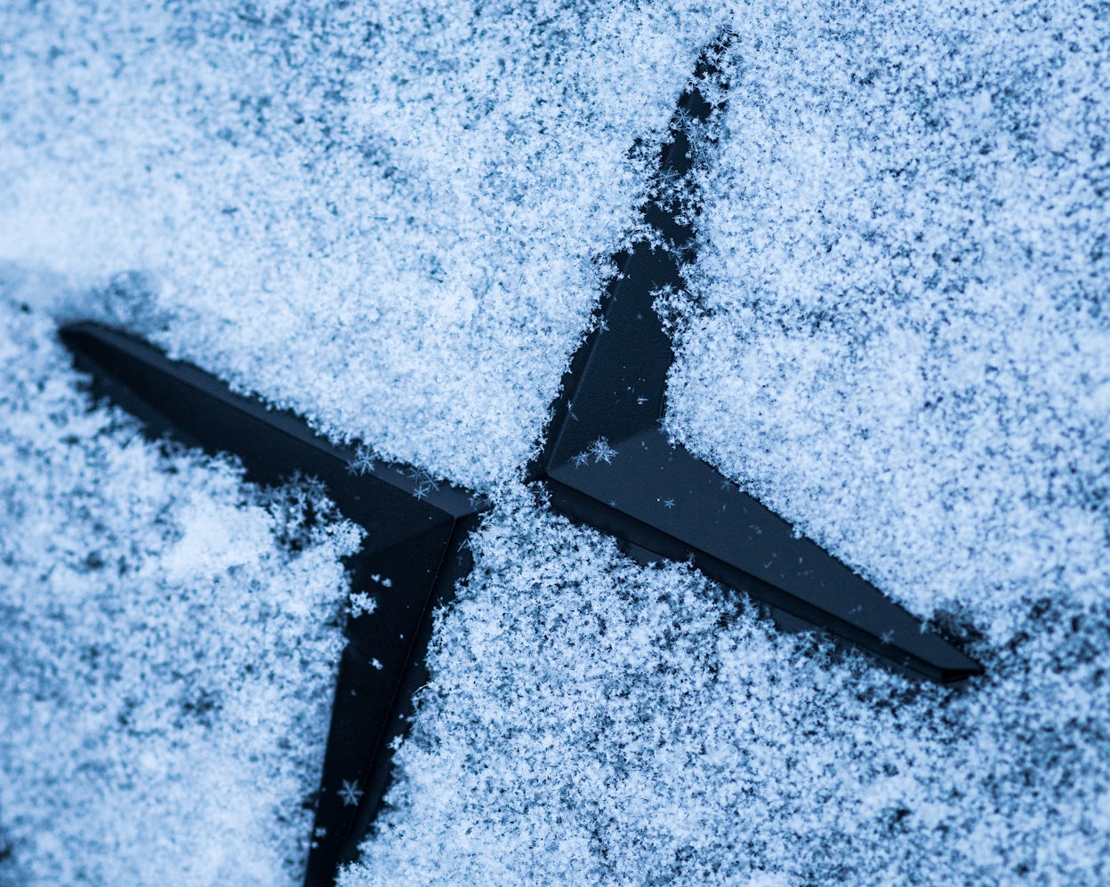 The Polestar logo, covered in snow.