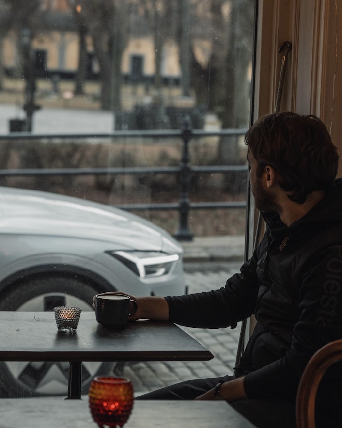 Man drinking coffee with Polestar 2 in the background