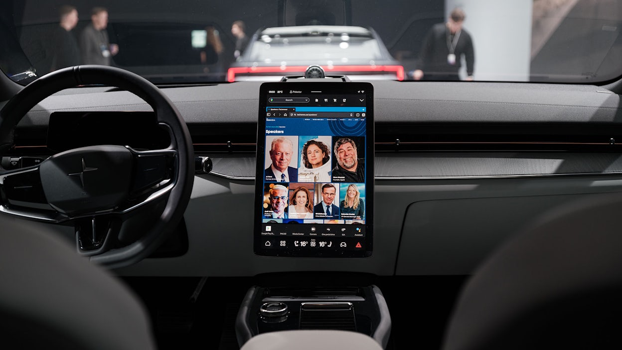 Photographed inside a Polestar 4, focusing on the steering wheel and dashboard display showing the speakers at The Tech Arena