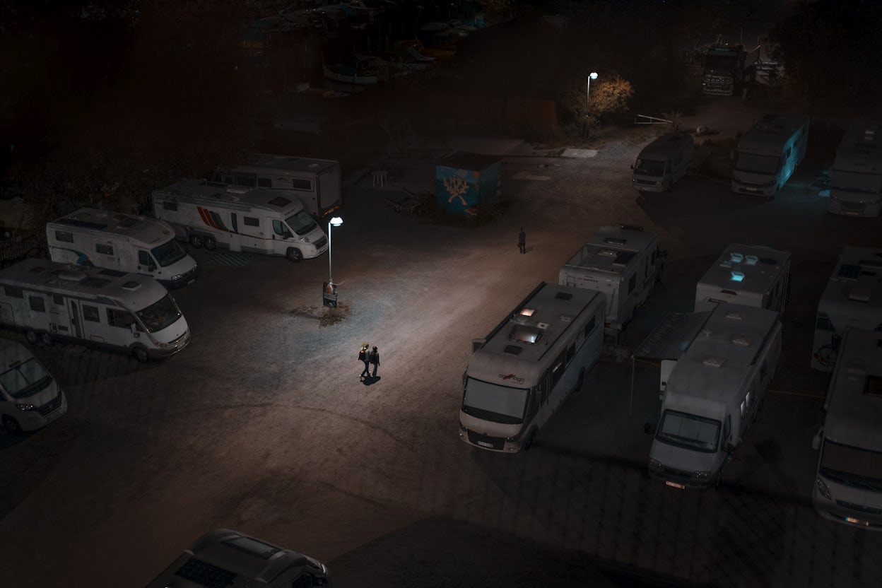 Three people walking through a dark caravan parking lot.