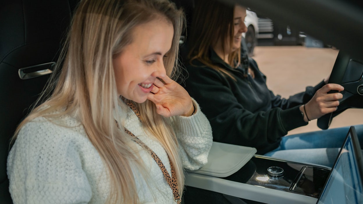 Two women in the Polestar 5 prototype, smiling.