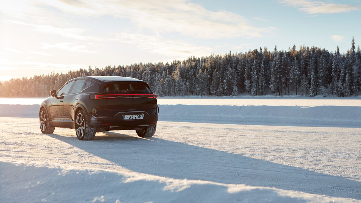 Polestar 3 in Space color driving on a snowy road with the sun shining