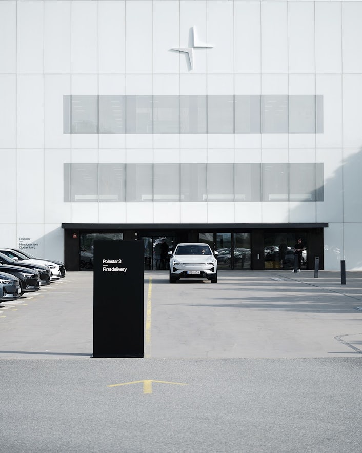 Polestar car parked in front of Polestar headquarters building with a sign reading Polestar 3 First delivery.