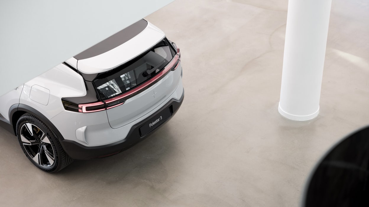 Rear view of Polestar 3 car with red tail lights in a minimalistic indoor space with white column and beige floor.