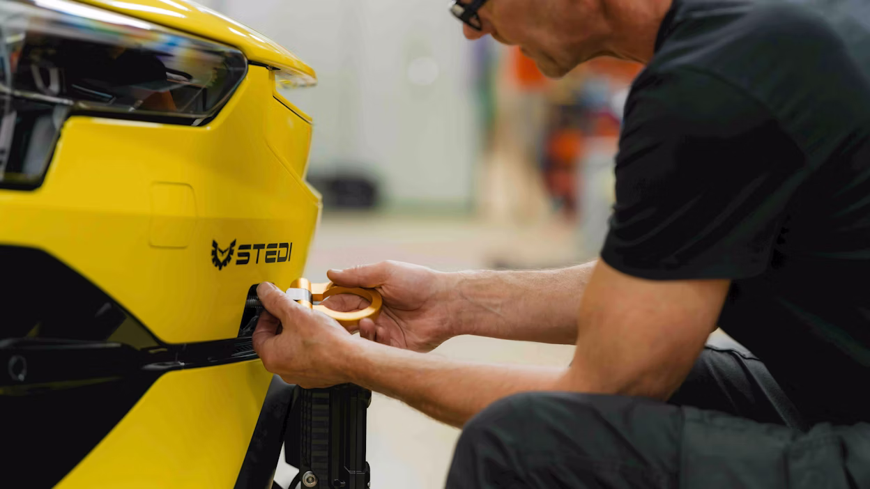 An engineer attaching a tow hook to the front of a car