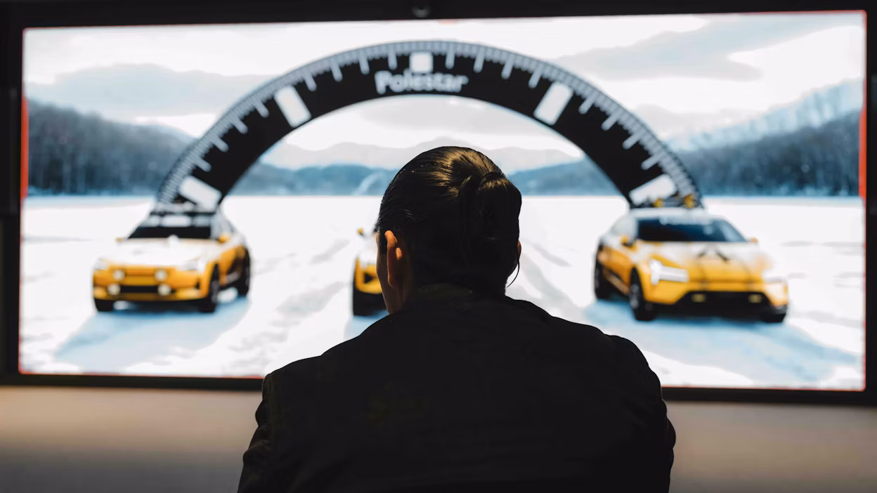 A designer looking at renderings of new cars on a large screen