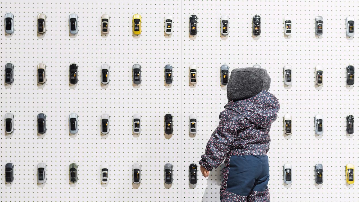 A child playing with a wall of miniature Polestar cars on wall