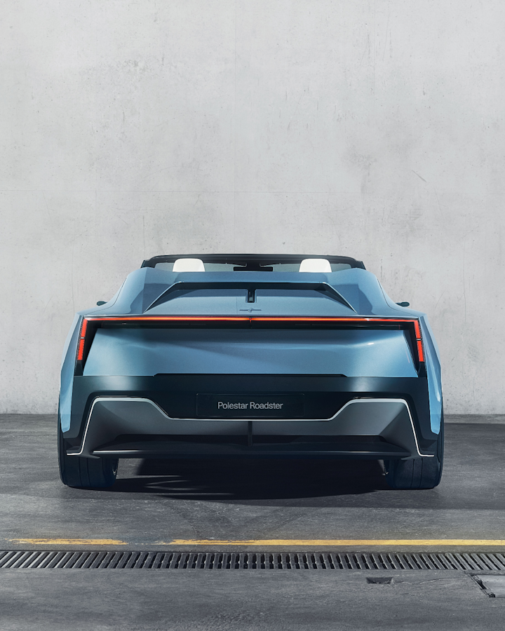 A rear view of Polestar 6 with a “Polestar Roadster” number plate facing a white concrete wall.