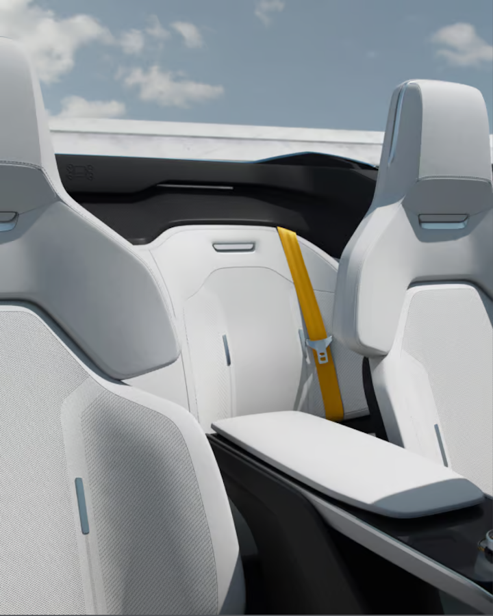 Polestar 6’s front seats with Swedish gold safety belts and a backdrop of blue skies with clouds.