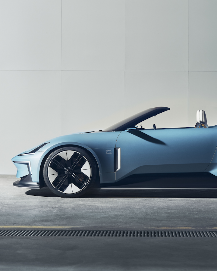 A side profile of Polestar 6 in light blue colour facing left while standing against a white wall.