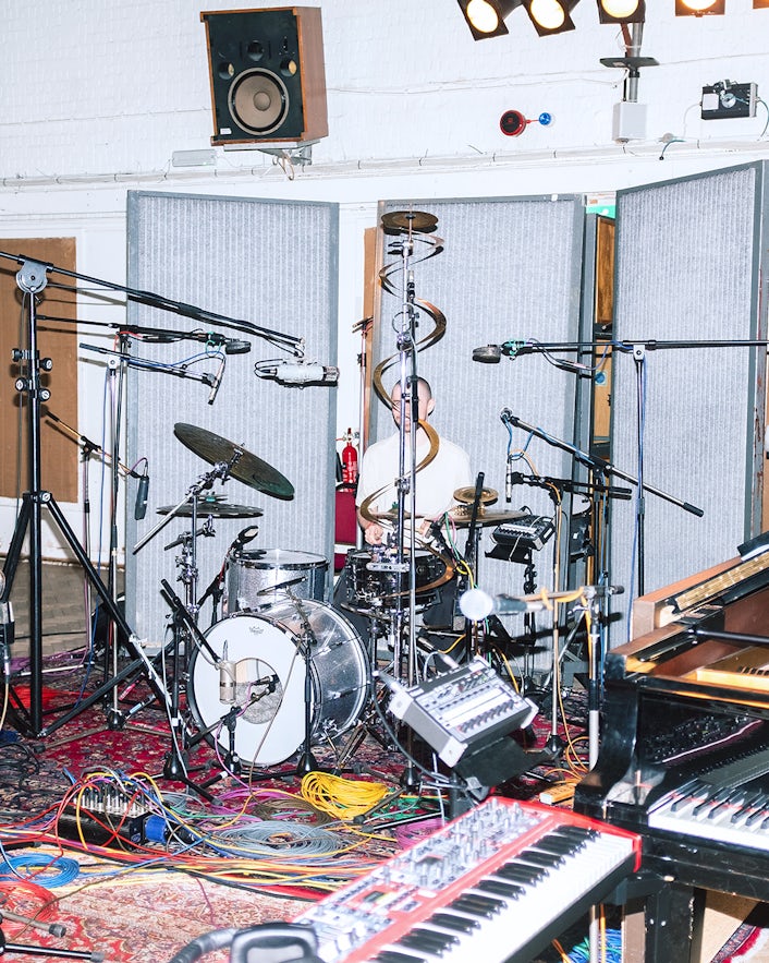 Man playing drums surrounded by equipment in studio