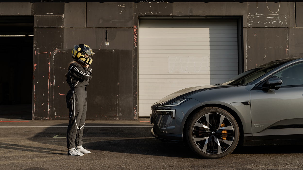 Woman in racing outfit standing in front of Polestar 4