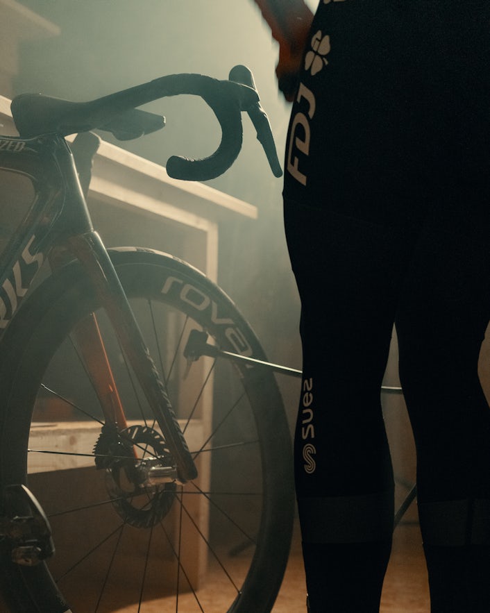 Legs of cyclist standing in front of racing bike
