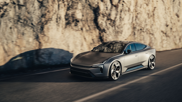 Polestar 5 car driving on a road beside a rocky wall.