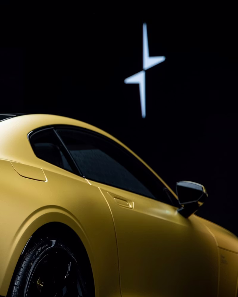 Yellow Polestar car with side mirror visible, Polestar logo in white on black background.