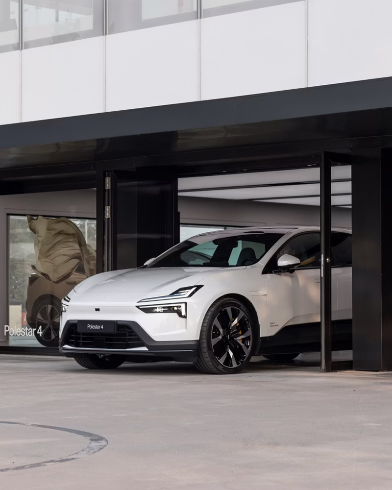 Polestar 4 car parked in front of a building with glass windows and open doors.