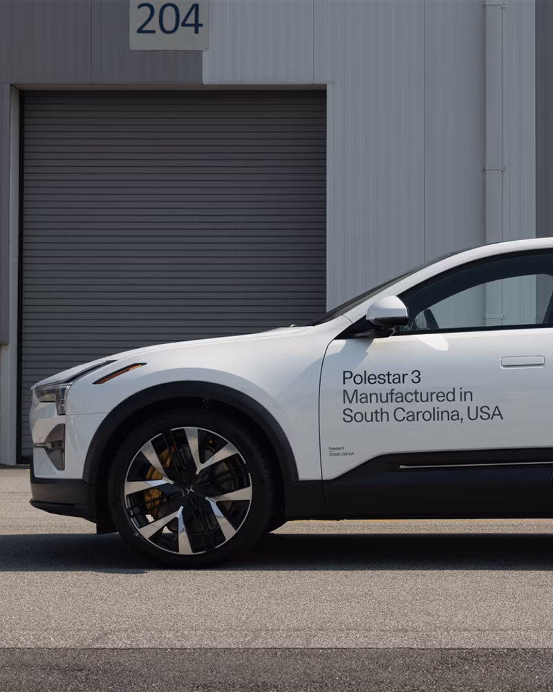 Polestar 3 car parked near a building with a closed garage door labeled 204, text on car indicates manufacturing in South Carolina, USA.