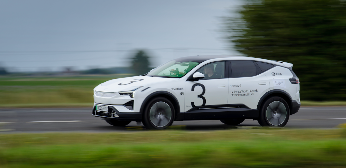 White Polestar 3 with text on the body driving on a road during a cloudy day.