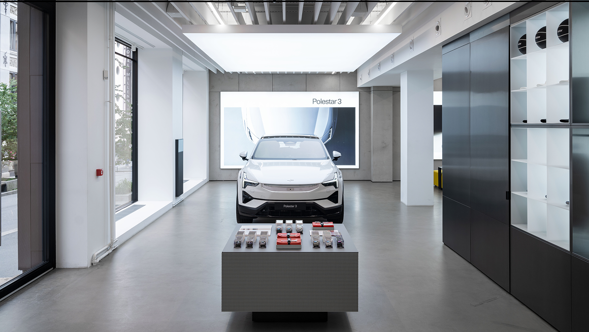 Polestar 3 displayed in a Space with a table of items in the foreground and shelves on the right.