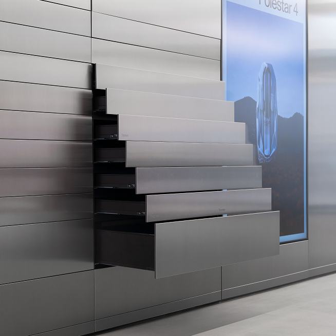 Metallic drawers extended from a wall next to a screen displaying Polestar 4 text and an abstract design.