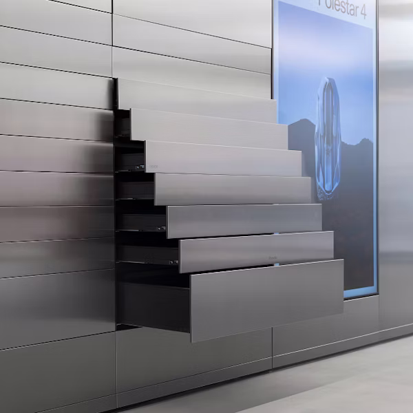 Metallic drawers extended from a wall next to a screen displaying Polestar 4 text and an abstract design.