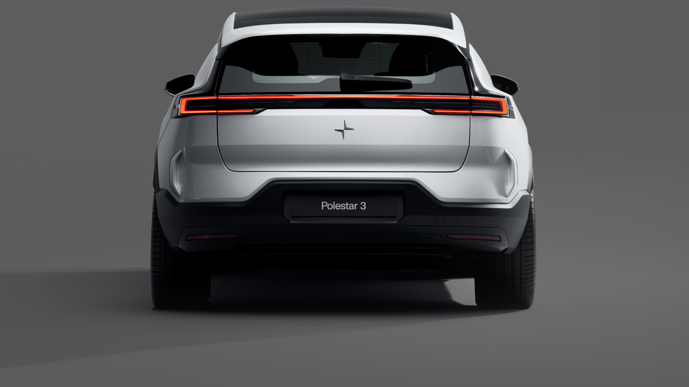 A rear view of a white Polestar 3 standing against a grey background.
