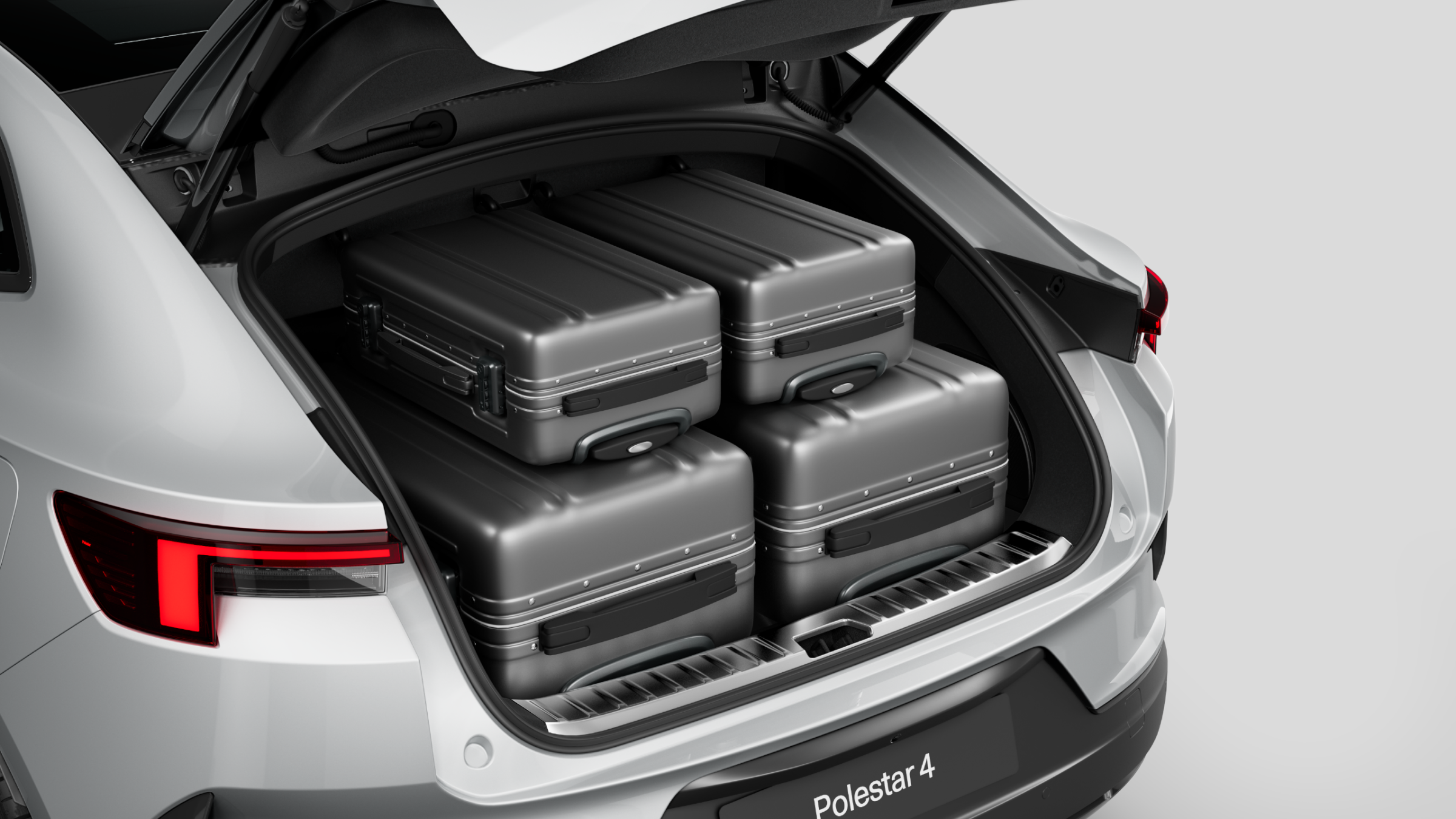 Polestar 4 coupé’s rear luggage compartment with two full-sized suitcases and smaller suitcases.