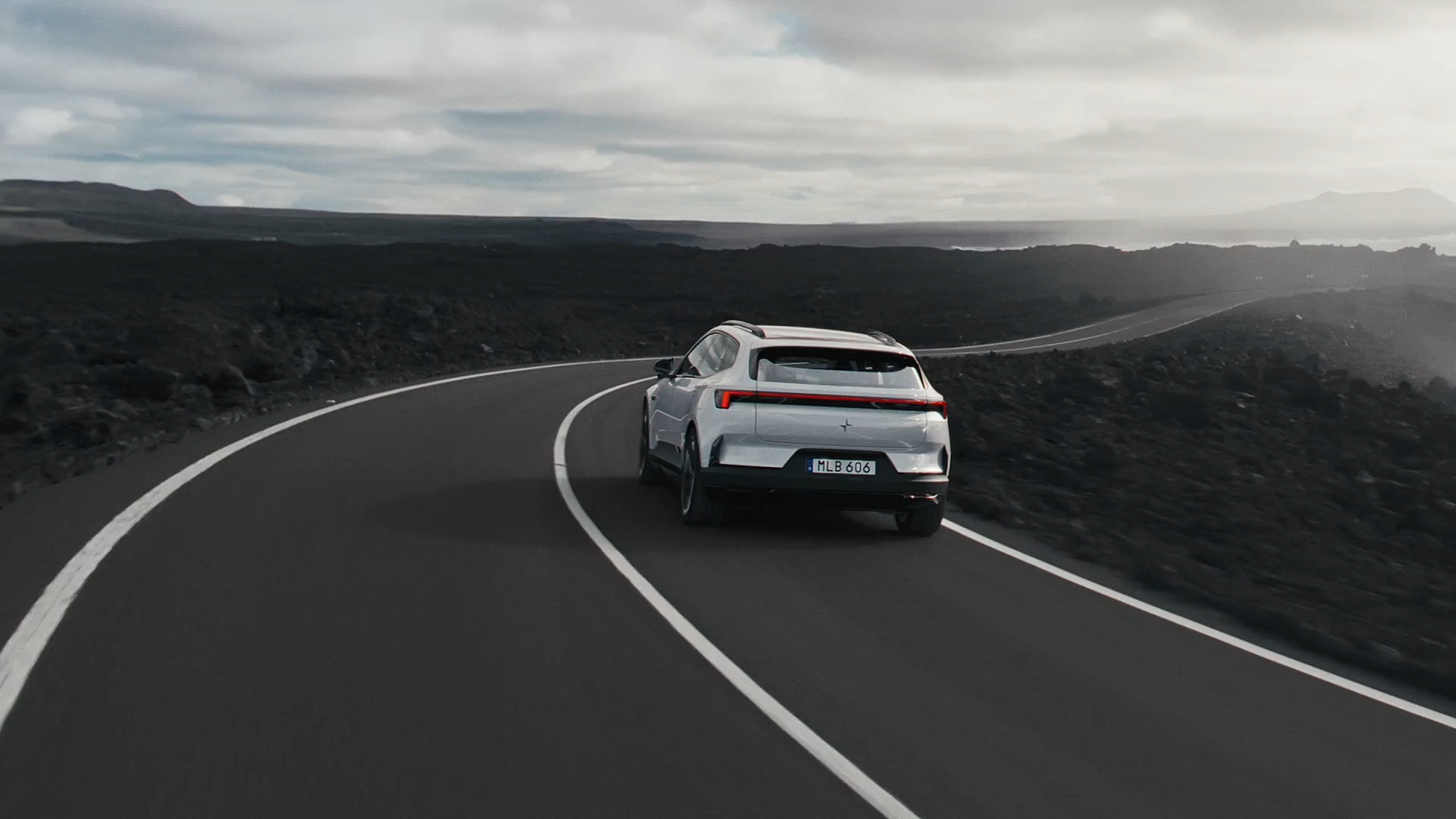 Polestar 4 SUV driving on a highway by the ocean.