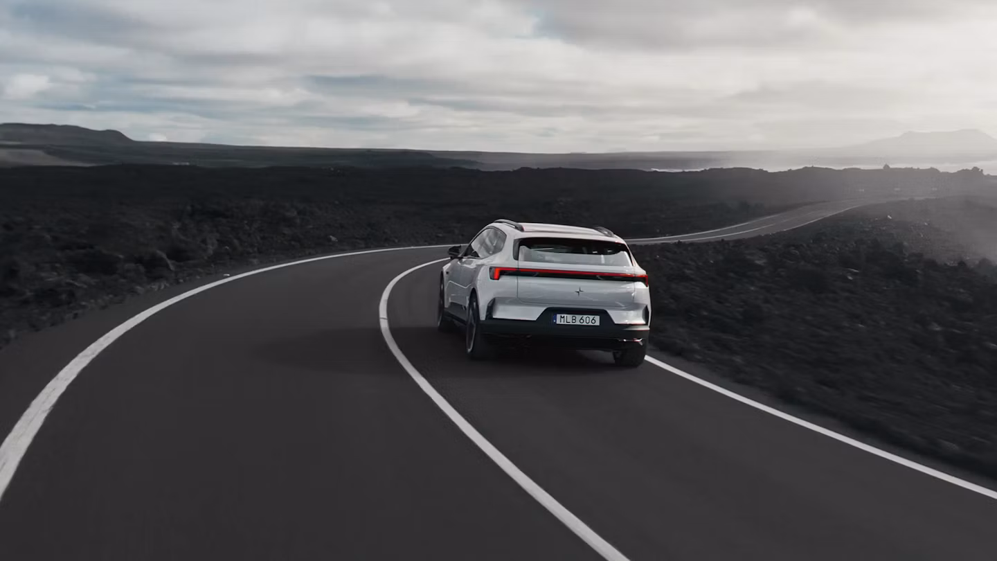 Polestar 4 SUV driving on a highway by the ocean.
