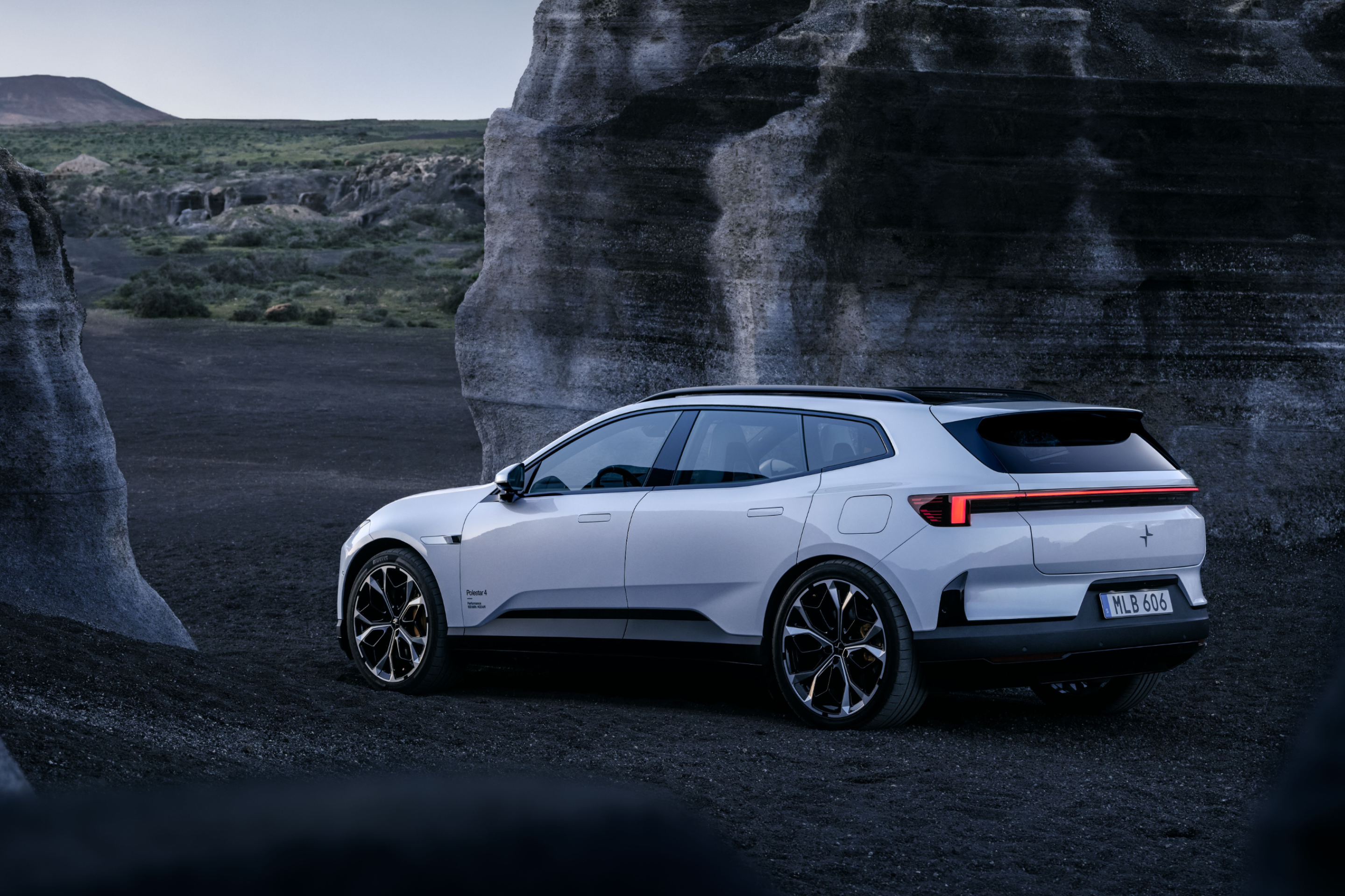 A white Polestar 4 SUV standing in between grey rock formations.